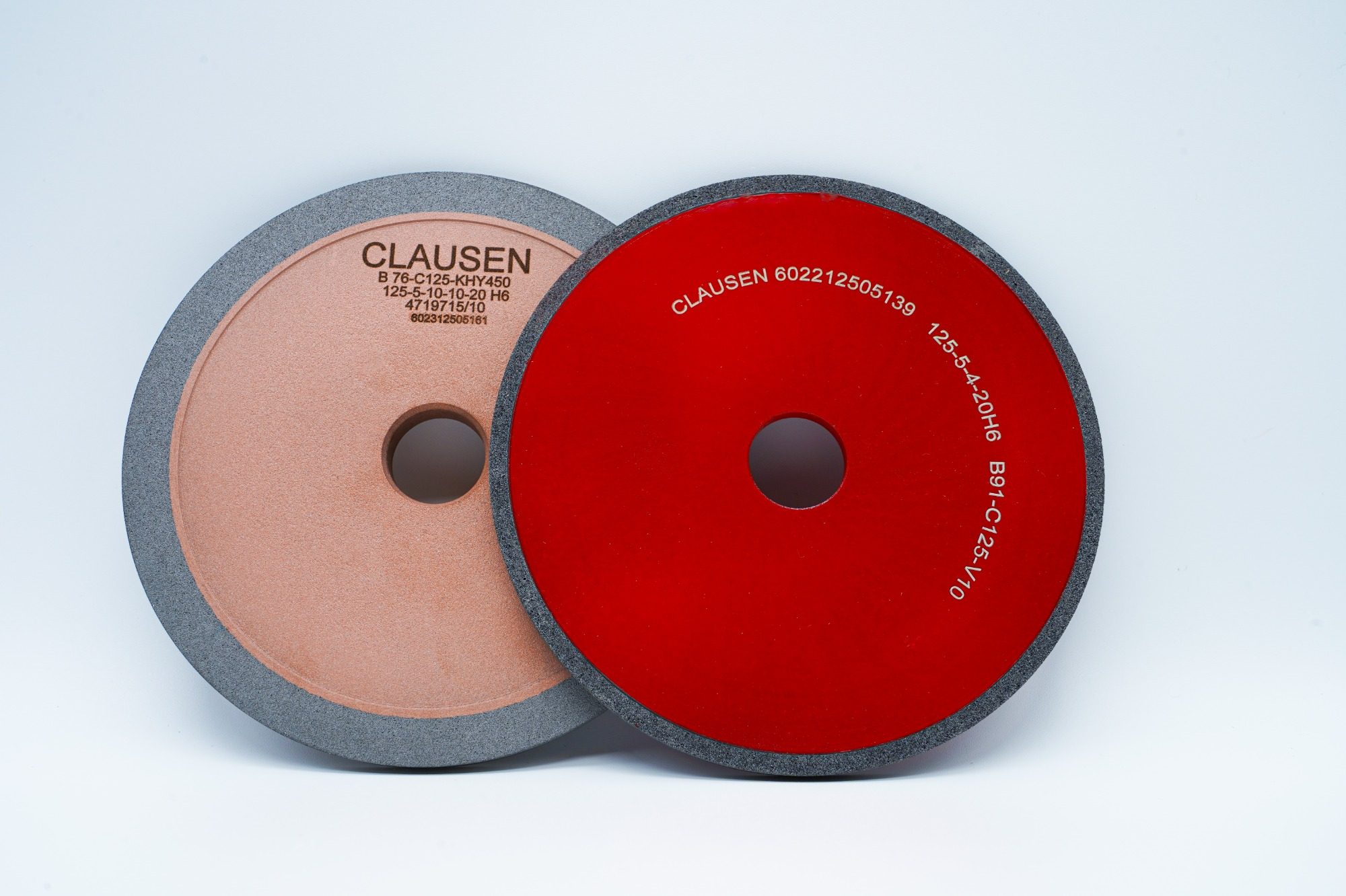 CBN Schleifscheiben Zwei Schleifscheiben, eine hellbraun und eine rot, mit zentralem Befestigungspunkt.