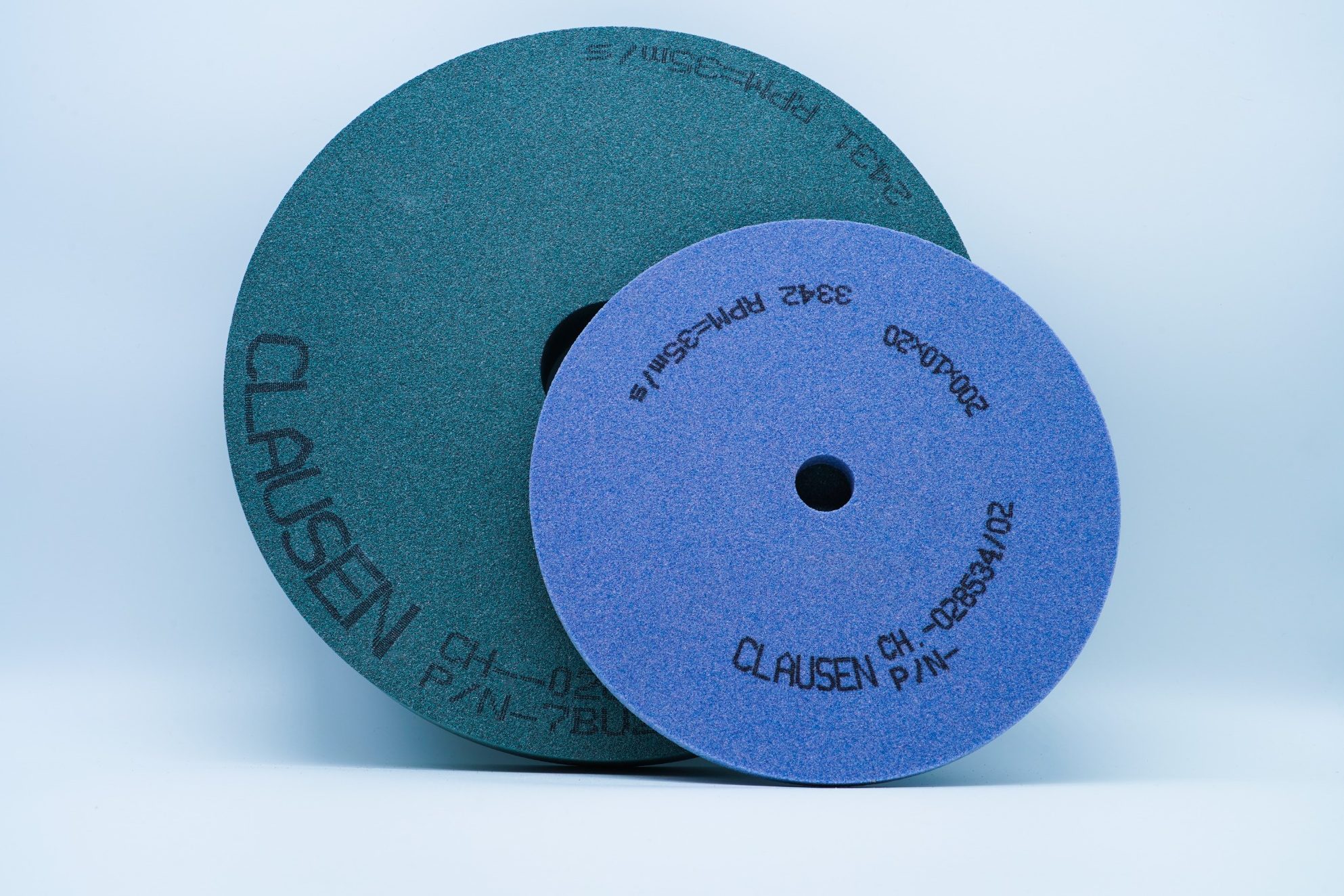 Keramische Schleifscheibe Zwei Schleifscheiben in grün und lila, übereinander gestapelt auf hellem Hintergrund.